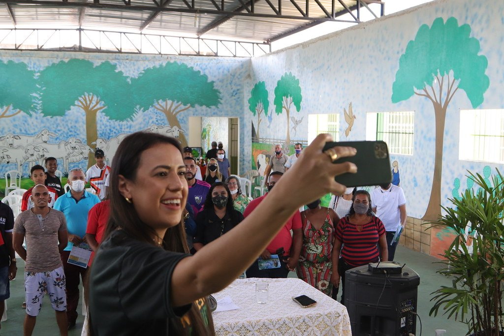 Talita Oliveira grava vídeo com o público durante encontro em salão comunitário